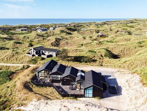 Uma propriedade costeira com várias casas, um caminho de acesso de areia e vista para o mar.