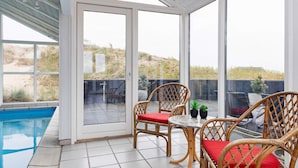 Un patio techado con piscina, muebles de mimbre y vistas al paisaje.