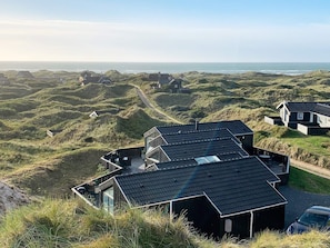 A coastal property with multiple buildings, including a prominent house with a sloped roof and a visible outdoor seating area.