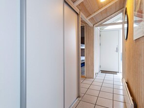 A hallway with a tiled floor, a white door, and a wooden ceiling. - 4 Star Holiday Home in Saltum (Saltum)