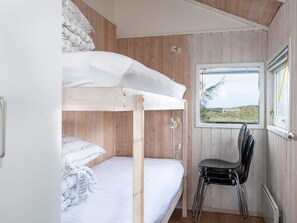 Un lit superposé avec une fenêtre, une chaise et un mur en bois.