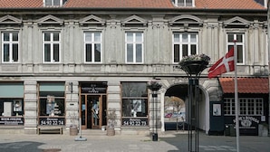 Il s'agit d'un bâtiment historique abritant plusieurs commerces, dont une pharmacie et un restaurant.