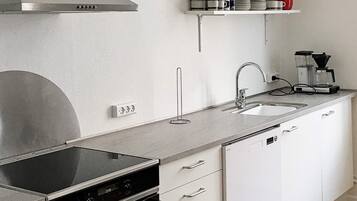 A modern kitchen with a built-in oven, a stainless steel range hood, a double sink, and a coffee maker on the countertop.