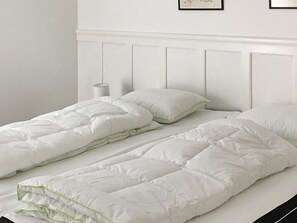 A bed with a white headboard and a white duvet.