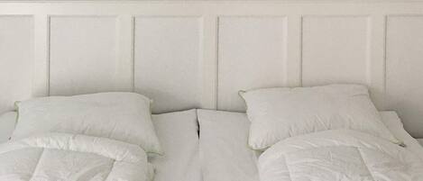 A room with two beds, each with white bedding and pillows.