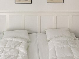 Una habitación con dos camas, cada una con ropa de cama y almohadas blancas.