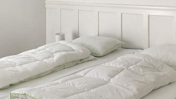 A bed with a white headboard and a white duvet.