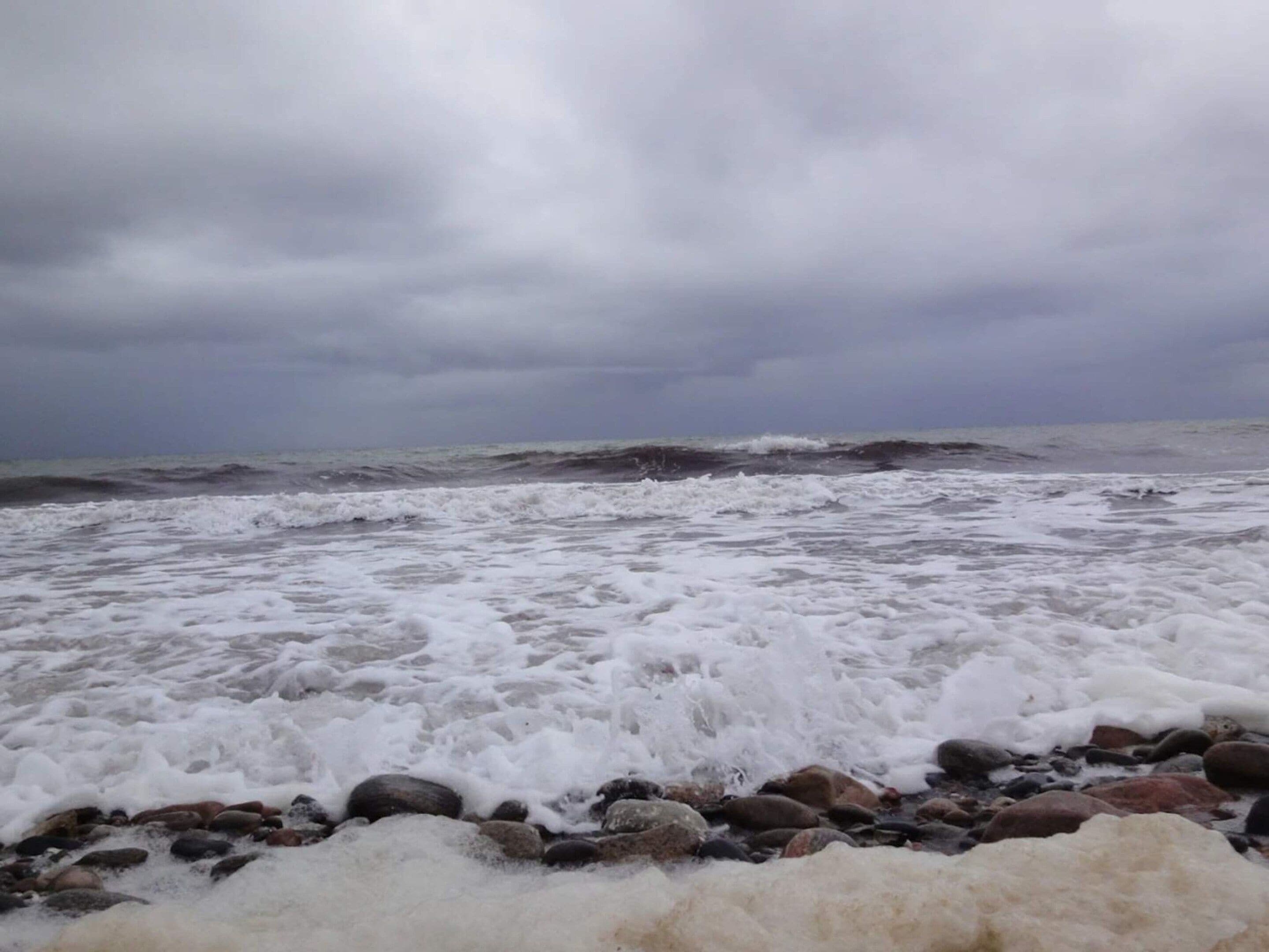 Un rivage rocheux où les vagues s’écrasent contre les rochers sous un ciel nuageux.