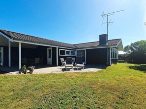 Una casa de dos pisos con un porche cubierto, una chimenea y una antena parabólica.