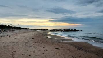 A beach with a rocky shoreline, a clear sky, and a distant horizon.