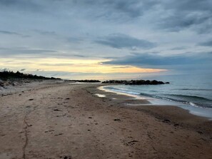 Una playa con costa rocosa, cielo despejado y horizonte lejano.
