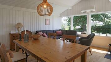 A dining area with a wooden table, chairs, and a hanging light fixture.