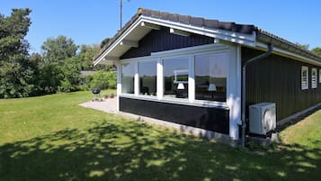 A single-story building with a covered porch, large windows, and an air conditioning unit.