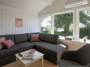 Una sala moderna con un sofá modular, una mesita de centro y un ventanal con vistas a zonas verdes.