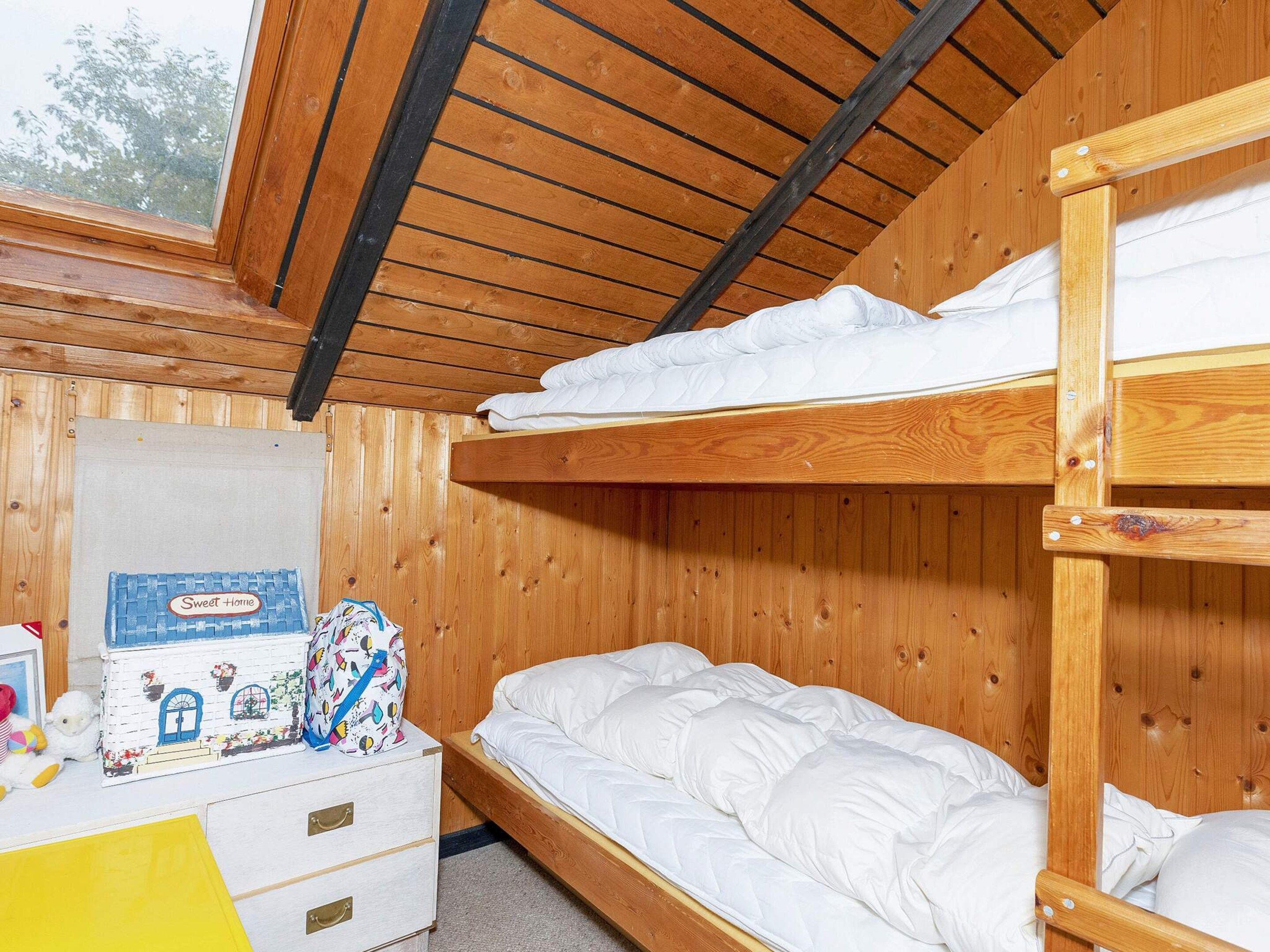 Une chambre avec des lits superposés, des murs en bois et un plafond en pente.