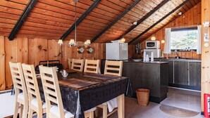 Une charmante cabane en bois dotée d’un coin repas, d’une cuisine et d’une fenêtre offrant une vue agréable.