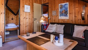 Une pièce chaleureuse avec des murs en bois, un lit, un canapé et une table sur laquelle se trouvent une lampe et des tasses.