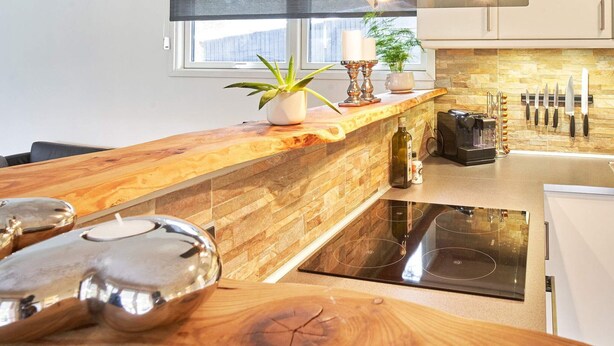 A modern kitchen with a wooden countertop, a built-in stove, and a range hood above the stove. - 4 Person Holiday Home in Aakirkeby (Akirkeby)