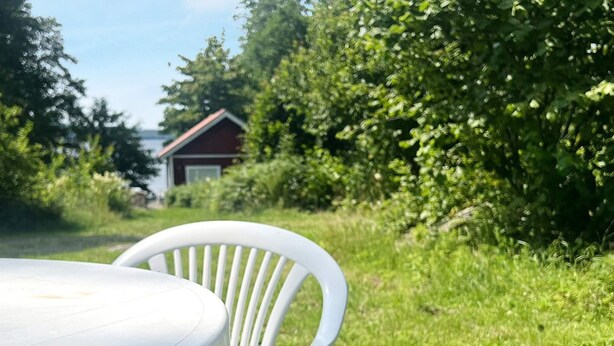 A white plastic chair and table in a grassy outdoor area with a house in the background. - 4 Person Holiday Home in Braas-by Traum (Braås)