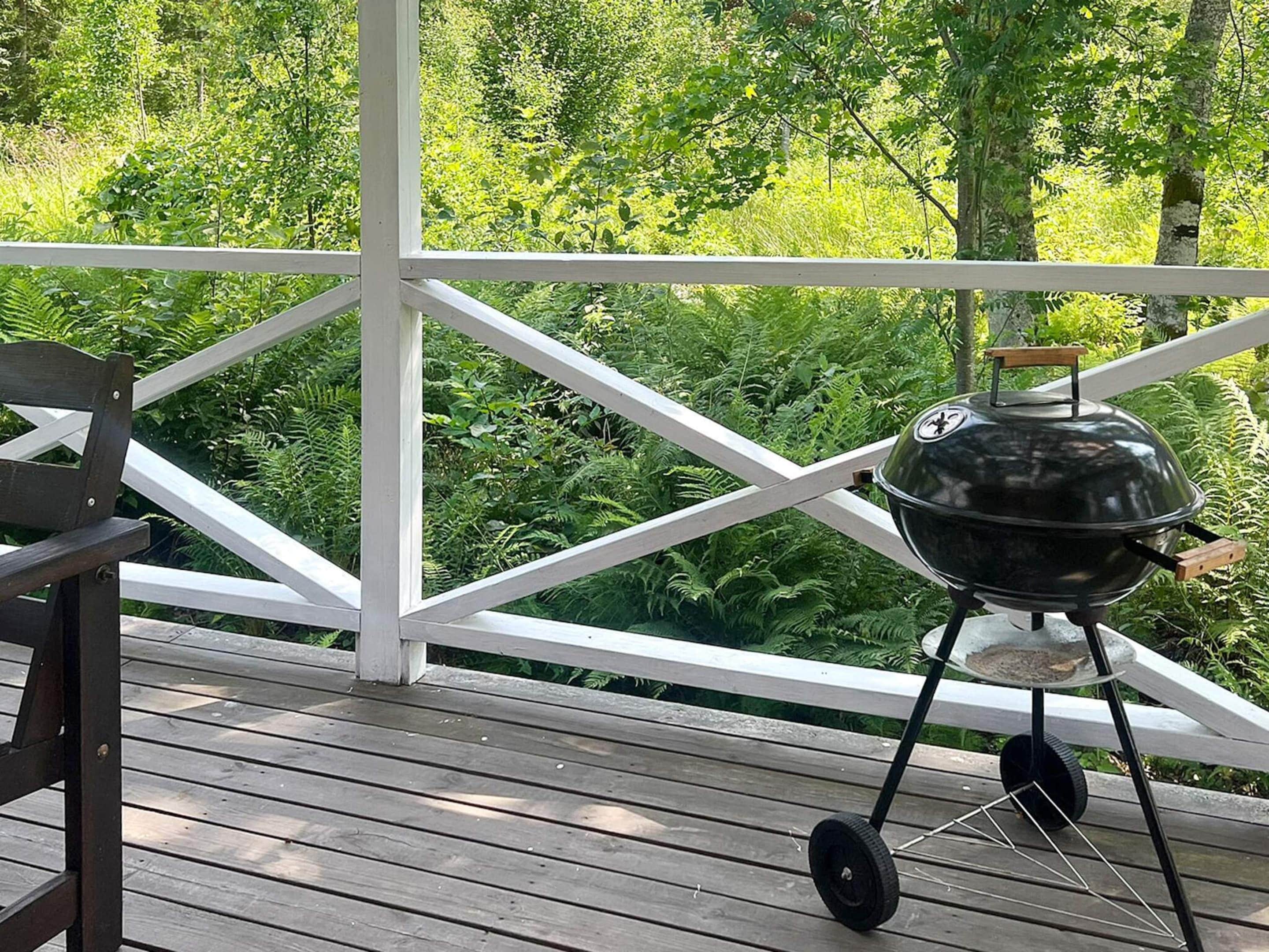 A wooden deck with a barbecue grill and a bench.