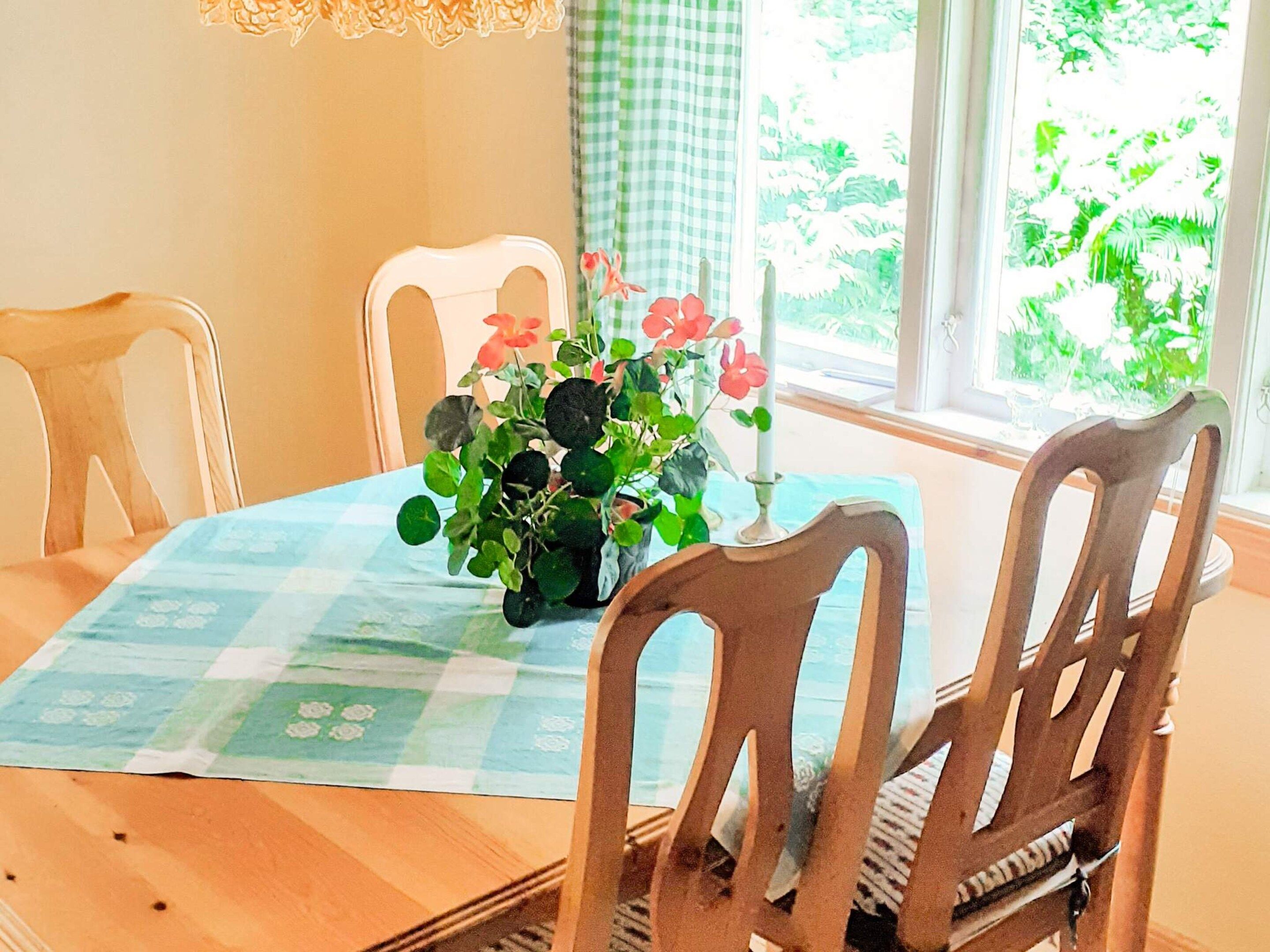 A dining table with a checkered tablecloth, surrounded by wooden chairs.