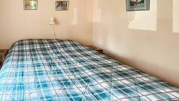 Un dormitorio con una cama, dos cuadros en la pared y una lámpara de noche.