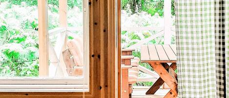 Une terrasse en bois avec une table et des chaises, entourée d’une végétation luxuriante.