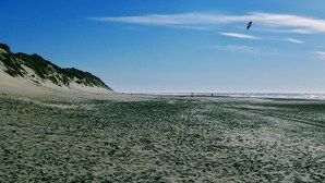 A beach with a sandy shore and a clear sky. - 6 Person Holiday Home in Ringkobing (Ringkobing)