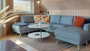 A modern living room with a sectional sofa, a round coffee table, and a rug. - 6 Person Holiday Home in Ringkobing (Ringkobing)