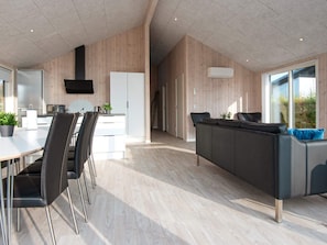 A modern kitchen with a dining area, wooden paneling, and a large window.