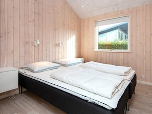 A bedroom with a bed, bedside tables, and a window with a view.