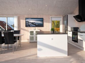 A modern kitchen with a central island, built-in appliances, and a large window with a view.