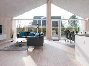 A modern living room with a sofa, coffee table, and a dining area with chairs. - 4 Star Holiday Home in Borkop (Borkop)