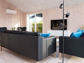 Una sala de estar moderna con un sofá de cuero negro, un televisor y una lámpara de pie.