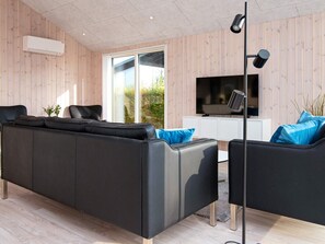 A modern living room with a black leather sofa, a television, and a floor lamp.