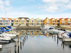 A marina with boats docked, a stone wall, and colorful buildings in the background. - 4 Person Holiday Home in Rudkobing (Rudkobing)