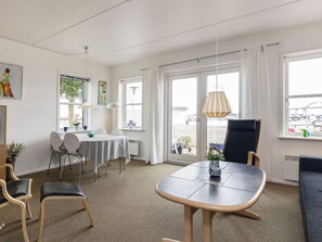 A modern hotel room with a dining area, a large window with a view, and a seating area with a table and chairs. - 4 Person Holiday Home in Rudkobing (Rudkobing)