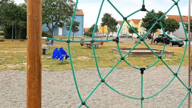 Uma área de recreação com uma estrutura de rede, um poste de madeira e uma área de brita.