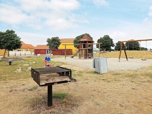 A playground with a swing set, climbing structures, and a fenced area. - 4 Person Holiday Home in Rudkobing (Rudkobing)