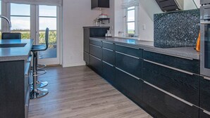 A modern kitchen with a large island, bar stools, and a view of the outdoors. - 5 Star Holiday Home in Ranum (Ranum)