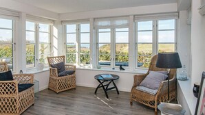 A sunlit room with wicker furniture, large windows, and a view of the countryside. - 5 Star Holiday Home in Ranum (Ranum)