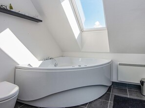 A modern bathroom with a freestanding bathtub, a toilet, and a window providing natural light.