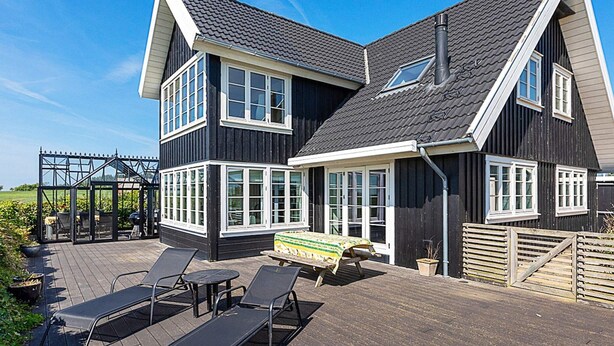 A two-story house with a dark exterior, white trim, and a sloped roof. - 5 Star Holiday Home in Ranum (Ranum)