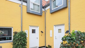 A yellow building with two doors, a window, and a potted plant. - 6 Person Holiday Home in Skagen (Skagen)