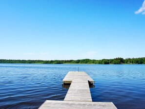 A wooden pier extending into calm water with a clear sky above.