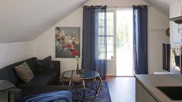 A modern living room with a sofa, a glass coffee table, and a painting on the wall.