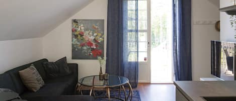A modern living room with a sofa, a glass coffee table, and a painting on the wall.