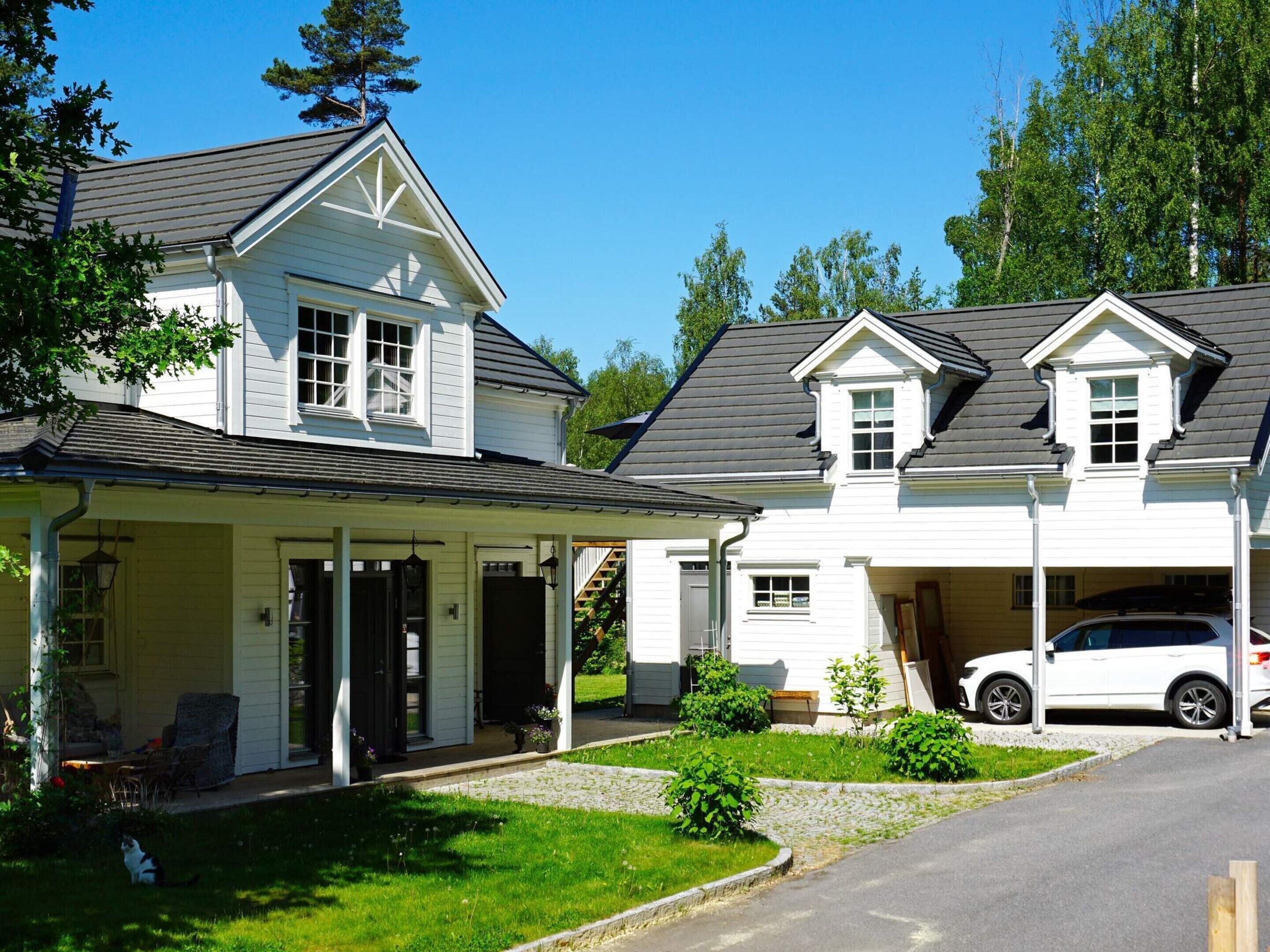 Une maison à deux étages avec un porche couvert, un garage et une voiture garée dans l’allée.