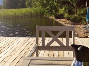 A wooden deck with a chair and a metal pitcher. - 4 Person Holiday Home in Rimbo (Rånäs)