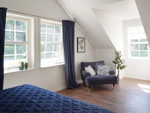 A bedroom with a large bed, a window with curtains, a dark-colored sofa, and a potted plant. - 4 Person Holiday Home in Rimbo (Rånäs)